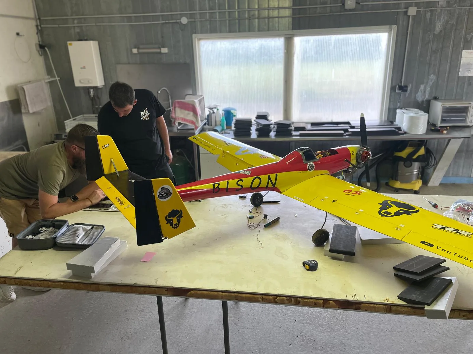Vue générale du Bison rouge et jaune posé sur une grande table d’atelier pendant les vérifications.