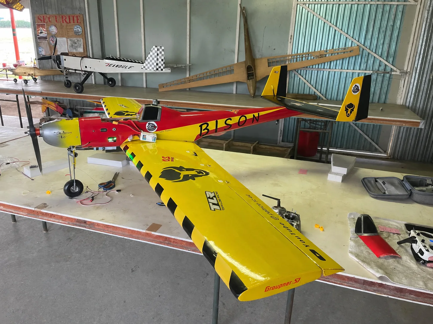 Le Bison rouge et jaune assemblé sur une table d’atelier, avec sa grande aile jaune et son fuselage marqué BISON.