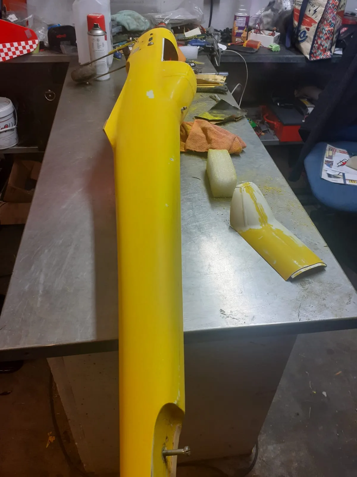 Fuselage jaune du Bison posé sur une table, avec une pièce de capot déposée à côté.